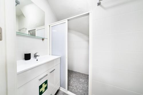 a white bathroom with a sink and a shower at Casa da Carochinha in Nazaré