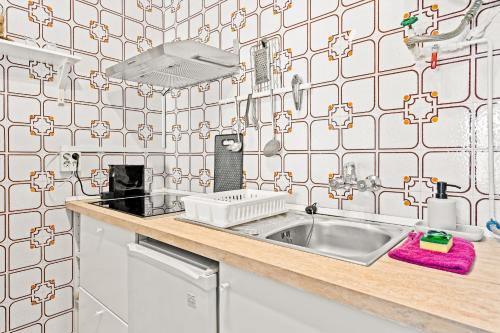 uma cozinha com um lavatório e uma parede de azulejos em Apartamento Welcs EMP-127-con vistas al canal em Empuriabrava