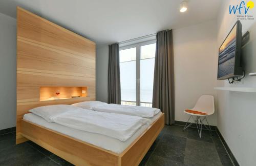 Un dormitorio con una cama grande y un televisor. en Haus Oldenburg Ferienwohnung 7, en Wangerooge