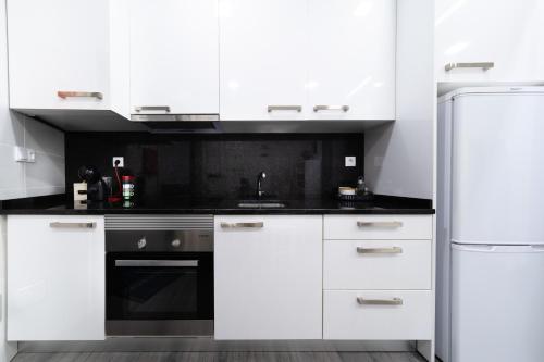 a white kitchen with white cabinets and a refrigerator at Casa da Carochinha in Nazaré