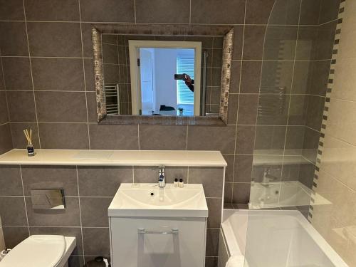 a bathroom with a sink and a toilet and a mirror at Cromwell Court Apartments in Huntingdon