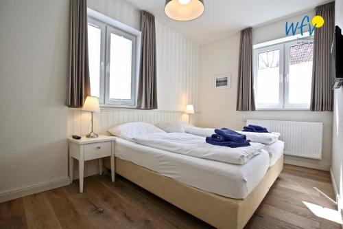 a bedroom with a large white bed with two windows at Alte Feuerwache Ferienwohnung 1 in Wangerooge