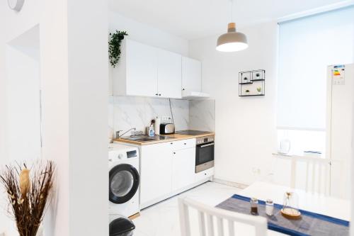 eine Küche mit weißen Schränken, einer Waschmaschine und einem Trockner in der Unterkunft Apartment Hafenarbeiter in Bremerhaven