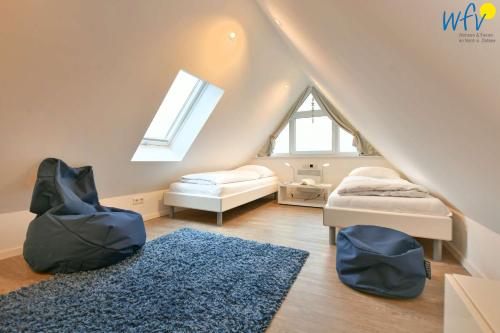 Cette chambre mansardée comprend 2 lits et un tapis bleu. dans l'établissement Bootshaus in den Duenen - 4 "Ferienwohnung Sonnendeck", à Wangerooge