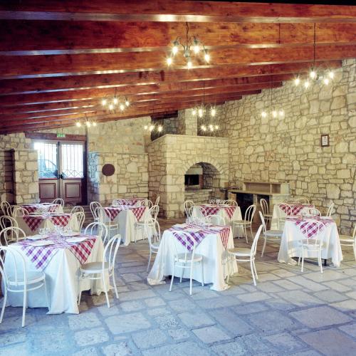 a room with tables and chairs and a stone wall at Masseria Mofetta in Acquaviva delle Fonti