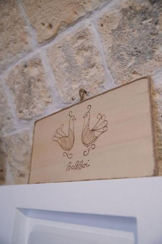 a sign with two roosters on a brick wall at Bobboi in Cagliari