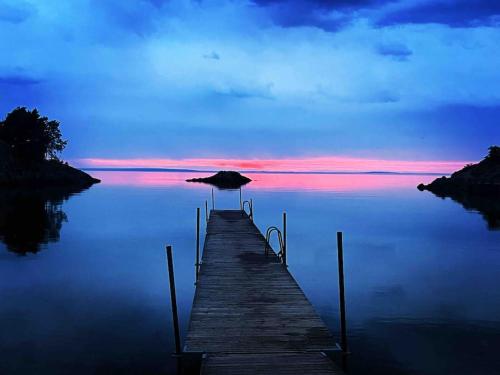 a wooden pier with an umbrella on the water at Hamnstuga i Hästholmens småbåtshamn in Ödeshög
