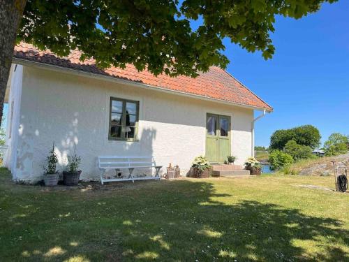 a white house with a bench in front of it at Hamnstuga i Hästholmens småbåtshamn in Ödeshög