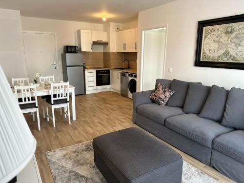 a living room with a couch and a table and a kitchen at Appartement F2 proche Paris CDG/parc expos/RER B in Sevran