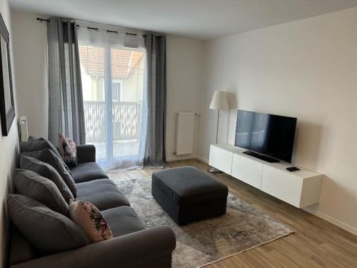a living room with a couch and a flat screen tv at Appartement F2 proche Paris CDG/parc expos/RER B in Sevran
