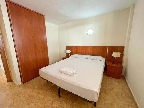Un dormitorio pequeño con una cama con cabecero de madera. en Apartamentos Marcomar 3000, en Alcossebre