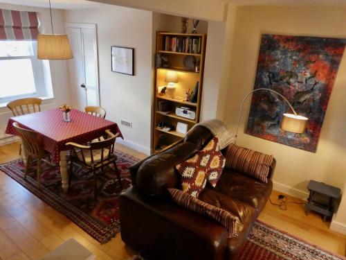 a living room with a table and a leather couch at Chic 2-bedroom townhouse in vibrant Abergavenny in Abergavenny