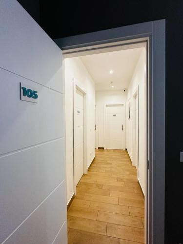 a hallway of an apartment with white walls and wood floors at Sunset Guest House in Reggio Calabria