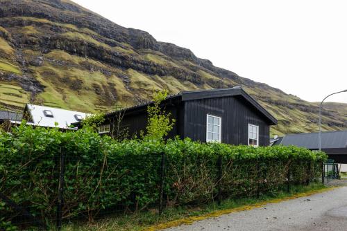 a black house in front of a mountain at Tranquil Village Retreat / Tjørnuvík in Tjørnuvík