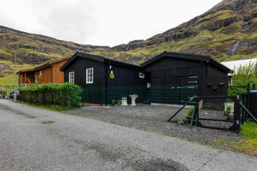 a couple of black buildings in front of a mountain at Tranquil Village Retreat / Tjørnuvík in Tjørnuvík