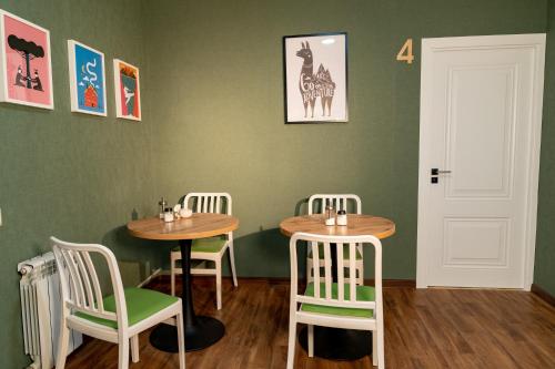 two tables and chairs in a room with green walls at Evergreen Hostel in Almaty