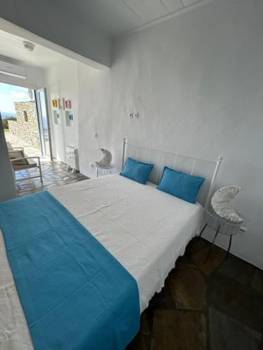 a bedroom with a large bed with blue pillows at Aggeliki's Cycladic Villa by Hostandros in Batsi