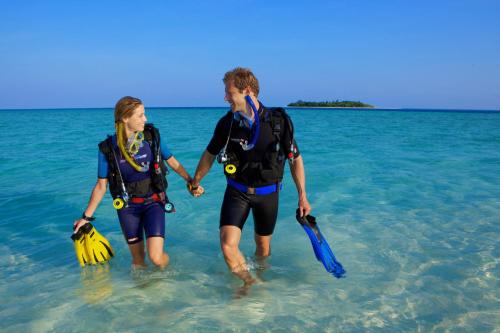 a man and a woman walking in the water at Kuredu Island Resort & Spa in Kuredu