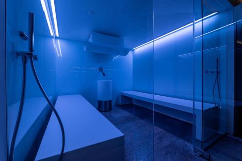 a blue bathroom with a shower and a bench at Swissôtel Damian Jasna in Demanovska Dolina