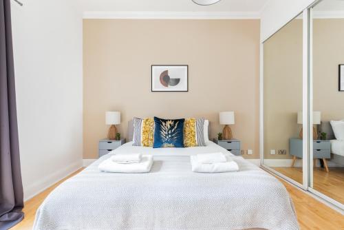 um quarto com uma grande cama branca com espelhos em The Clerkenwell Flats em Greenford