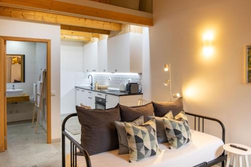 a room with a couch with pillows and a kitchen at Quinta da Capelinha Agroturismo in Tavira