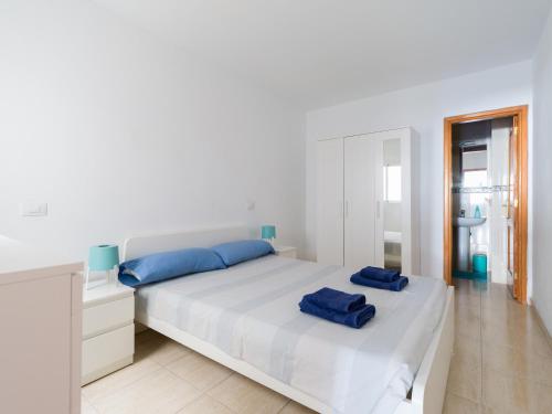 ein weißes Schlafzimmer mit einem Bett mit blauen Kissen darauf in der Unterkunft Apartamento Pura vida con WIFI Playas y compras in Vecindario