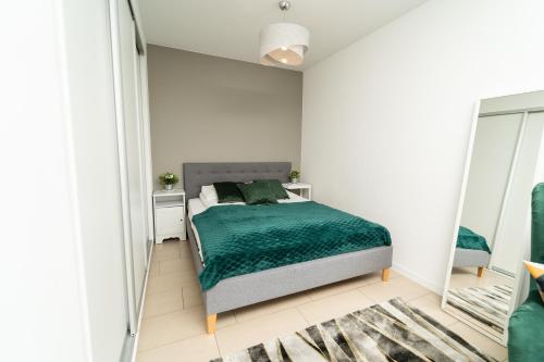 sypialnia z zielonym łóżkiem i lustrem w obiekcie Apartview Bukowa III by Rent like home w Wiśle