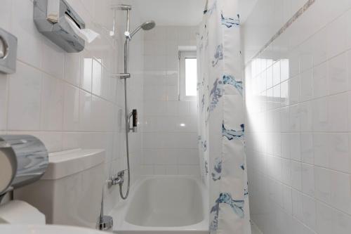 La salle de bains blanche est pourvue d'une douche et de toilettes. dans l'établissement Hotel Rossija, à Francfort-sur-le-Main