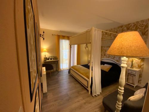 a bedroom with a canopy bed and a lamp at Maison d'Hôtes Domaine de Labelo in Commensacq