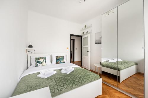 um quarto branco com uma cama grande e um espelho em Metro Płocka Comfy Apartment em Varsóvia
