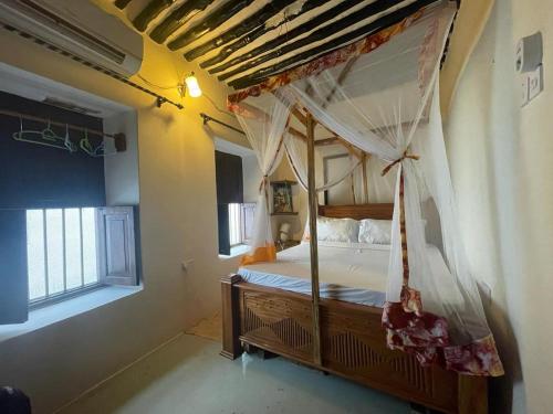 Four Seasons في Stone Town: غرفة نوم مع سرير مظلة ونافذة