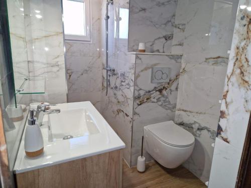 Baño blanco con aseo y lavamanos en La Villa Romantica Résidence de vacances Les Tres Cales Espagne, en Les tres Cales