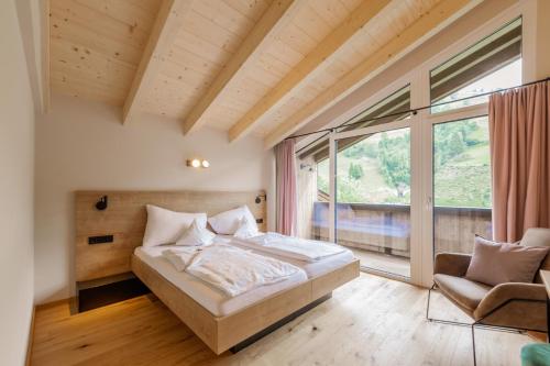 um quarto com uma cama e uma grande janela em Haus Jausern em Saalbach-Hinterglemm