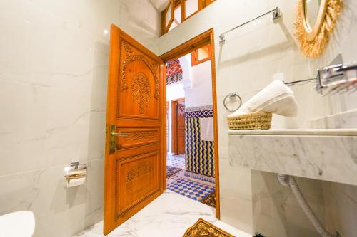 a bathroom with a wooden door and a sink at Villa Timskrine - Panoramic Mountains View in Marrakech