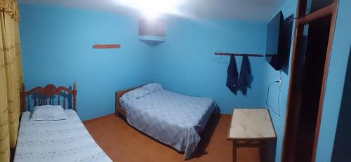 um quarto azul com duas camas e uma televisão em Shania em Trujillo