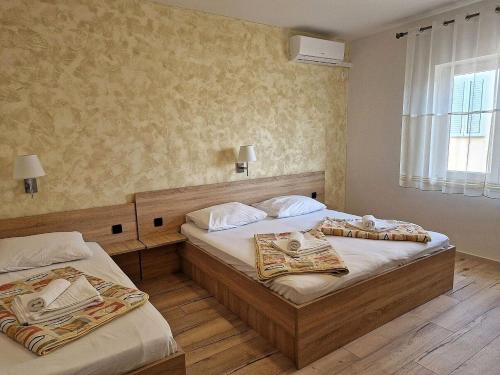 a bedroom with two beds and a window at Apartment and Rooms Amenka in Novalja