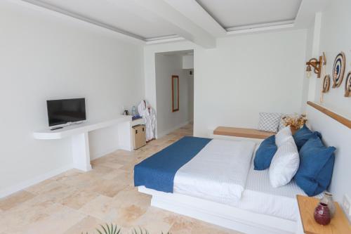 a white bedroom with a bed and a tv at Mavi Cam Hotel Ayvalik in Sefaçamlık