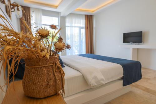 a bedroom with a bed and a vase with flowers on a table at Mavi Cam Hotel Ayvalik in Sefaçamlık