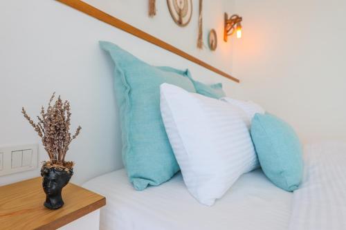 a bed with blue and white pillows and a vase at Mavi Cam Hotel Ayvalik in Sefaçamlık