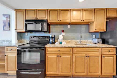 a kitchen with wooden cabinets and a black stove at Beachfront Luxury Condo w Private Balcony in Myrtle Beach