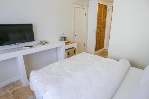 a white room with a tv and a white couch at Mavi Cam Hotel Ayvalik in Sefaçamlık