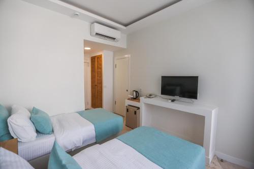 a hotel room with two beds and a flat screen tv at Mavi Cam Hotel Ayvalik in Sefaçamlık
