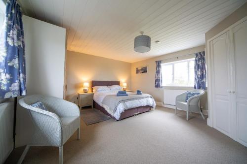 1 dormitorio con 1 cama, 2 sillas y ventana en Penrose Cottage en Bude