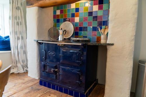 an old stove in a kitchen with colorful tiles at Penrose Cottage in Bude