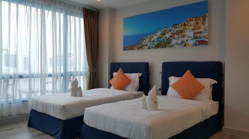 1 dormitorio con 2 camas y almohadas de color naranja y blanco en The Crest Santora Huahin 4 Fl H(Monthly rate), en Hua Hin