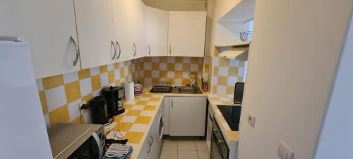 une cuisine avec des placards blancs et du carrelage jaune et blanc dans l'établissement T3 Riez, à Riez