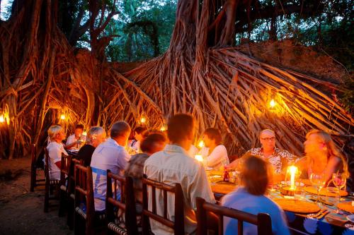 a group of people sitting at tables in front of a tree at Chole Mjini Treehouses Lodge in Utende