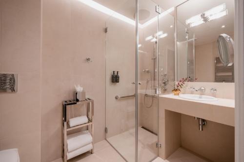 ein Bad mit einer Dusche und einem Waschbecken in der Unterkunft Hôtel De Buci in Paris