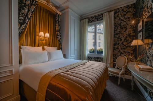 パリにあるHôtel De Buciのベッド、デスク、窓が備わるホテルルームです。