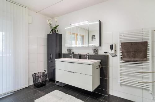 ein weißes Badezimmer mit einem Waschbecken und einem Spiegel in der Unterkunft Turmalin in Überlingen